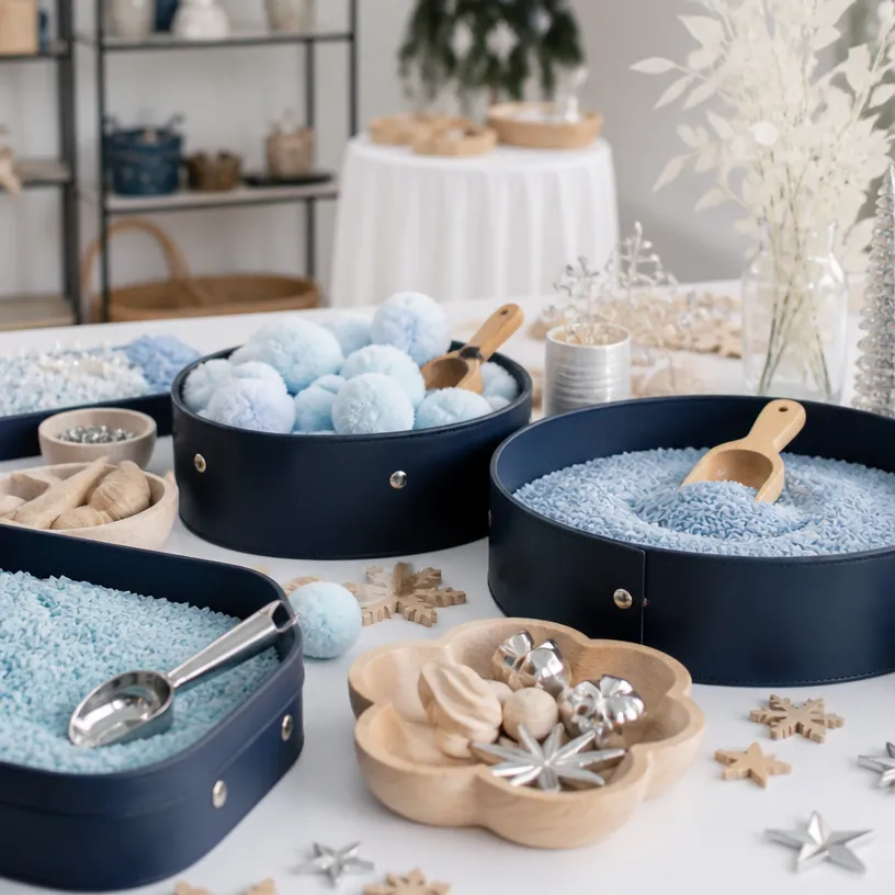 Blue sensory play materials arranged in navy activity bins